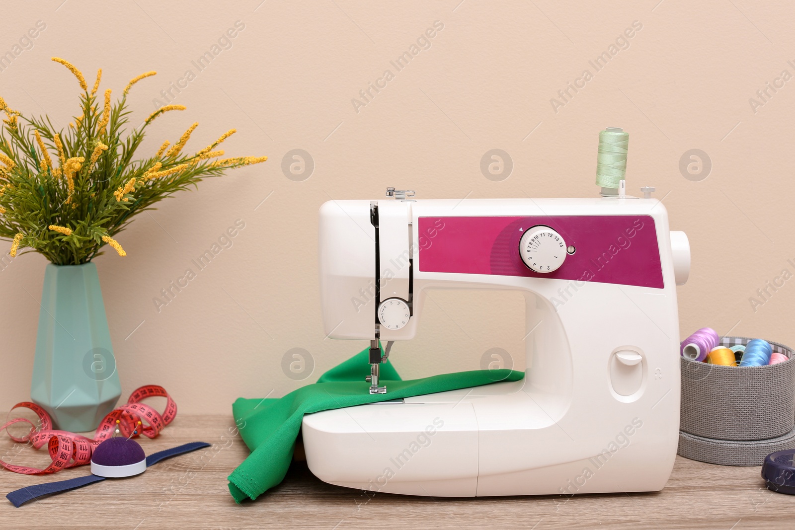 Photo of Modern sewing machine on table against light background