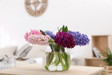 Photo of Beautiful hyacinths in glass vase on table indoors. Spring flowers