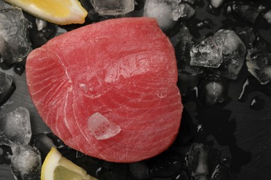 Photo of Raw tuna fillet and ice cubes on black table, top view