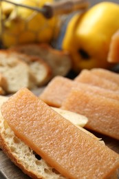 Tasty sweet quince paste, bread and fresh fruits on wooden board, closeup