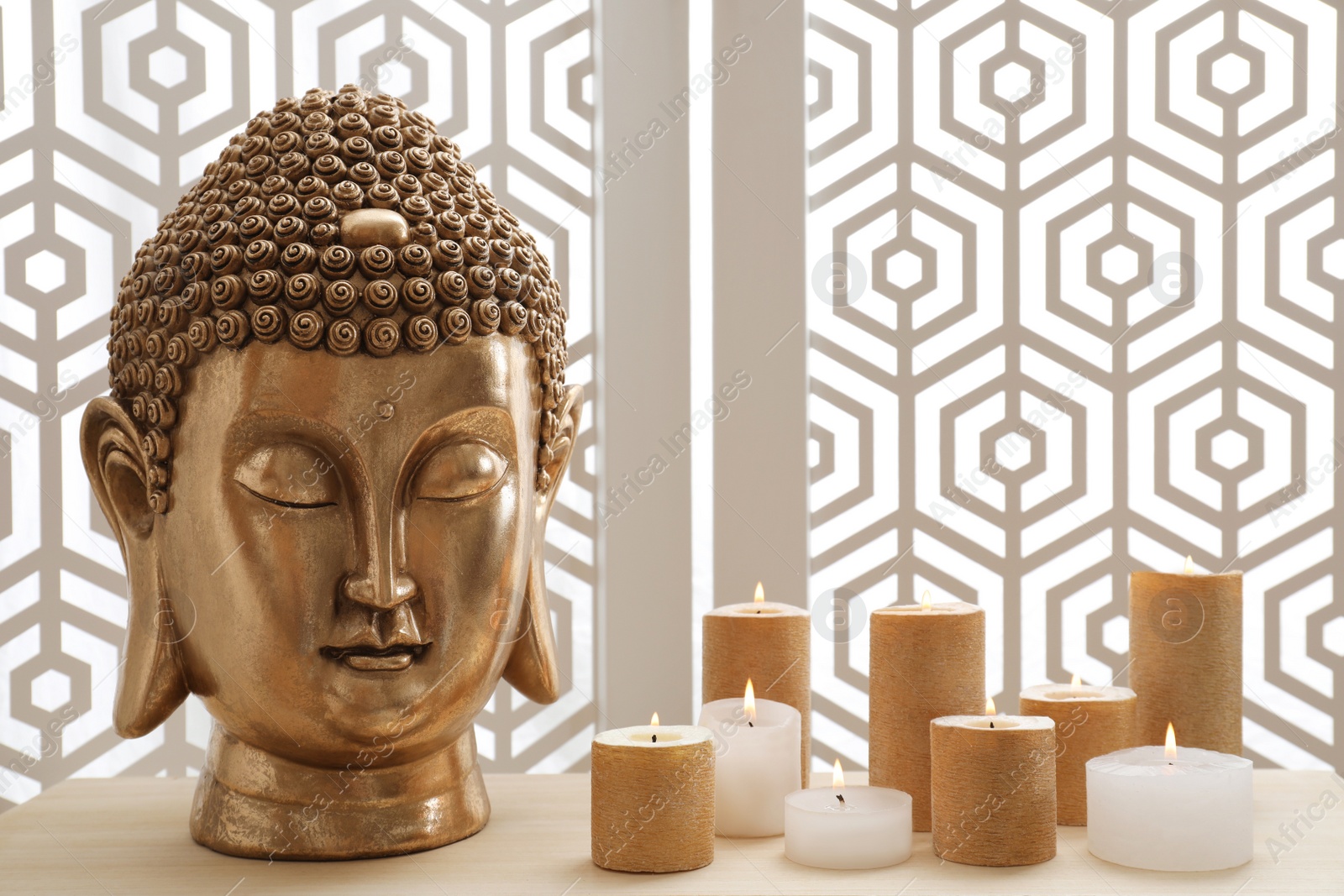 Photo of Buddha statue and burning candles on table indoors