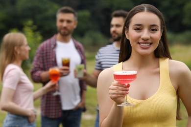 Photo of Friends having cocktail party outdoors. Happy woman with glass of drink, selective focus