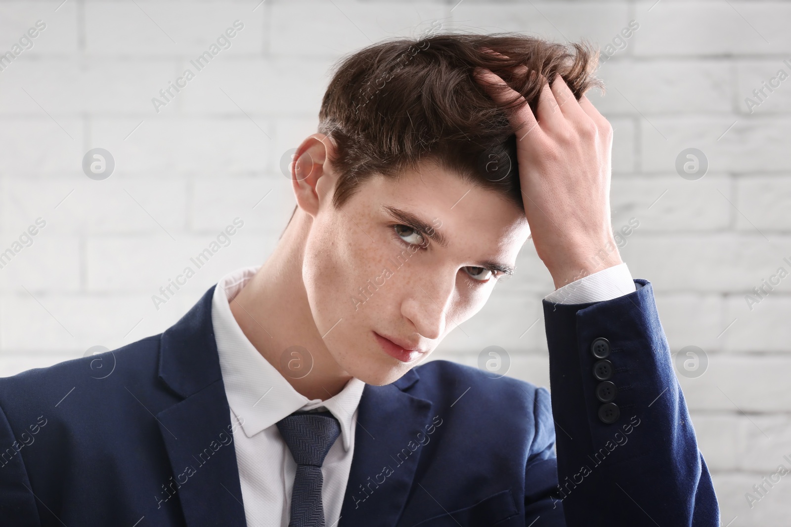 Photo of Portrait of young businessman with beautiful hair on brick wall background