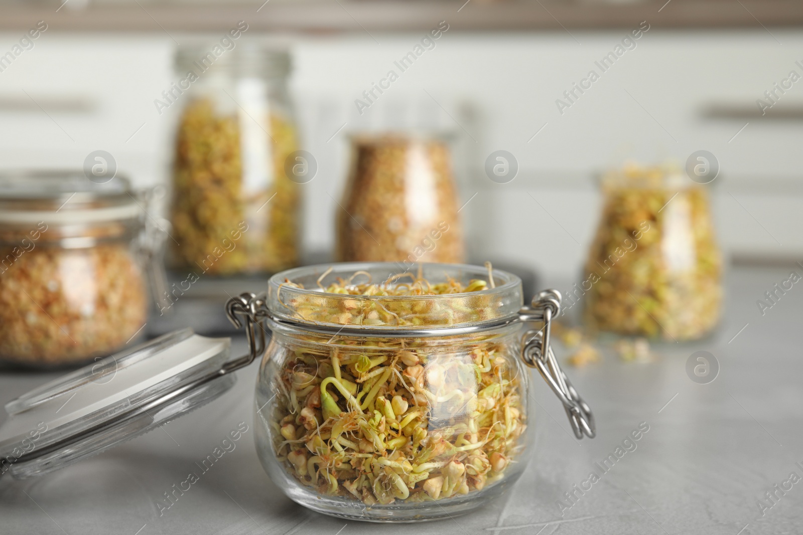 Photo of Glass jar of sprouted green buckwheat on light grey table