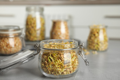 Glass jar of sprouted green buckwheat on light grey table