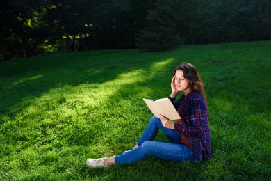 Photo of Young woman reading book in park on sunny day