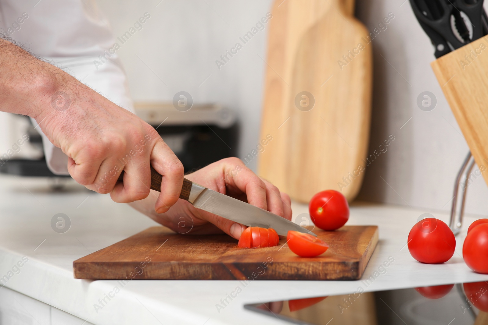 Photo of Professional chef cutting tomatoes in kitchen, closeup