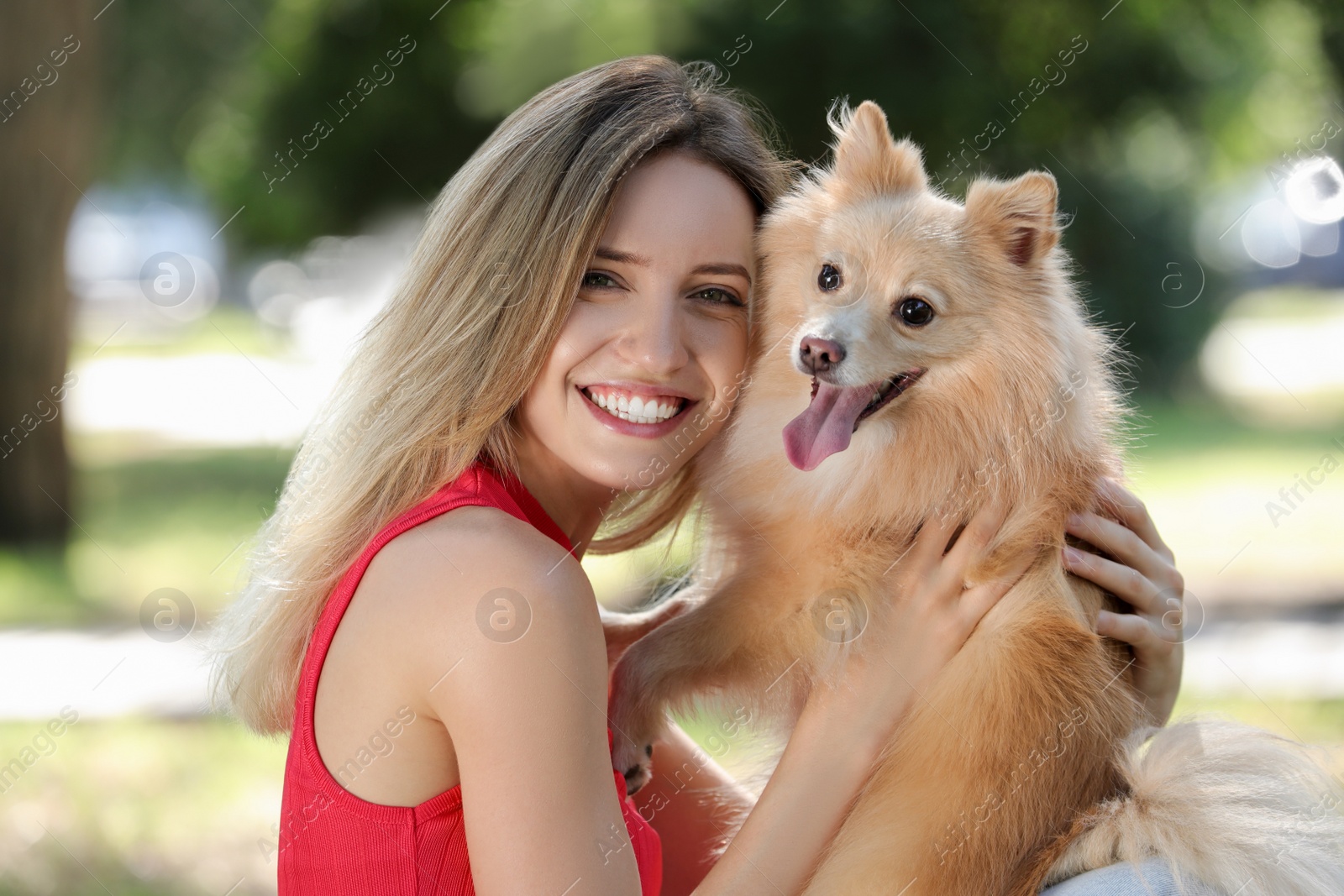 Photo of Young woman with her cute dog in park on sunny day