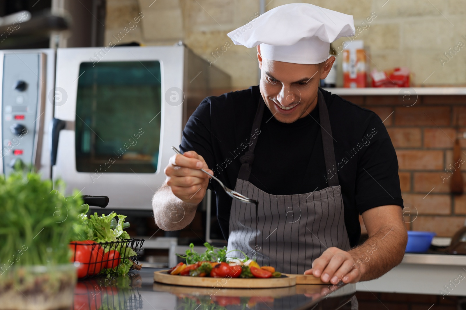 Photo of Professional chef decorating cooked dish with sauce in restaurant kitchen