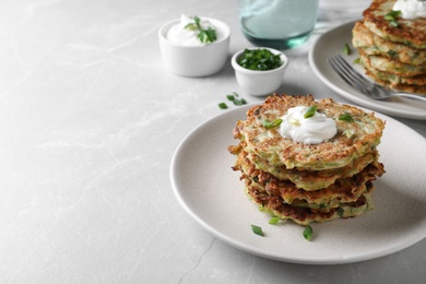Photo of Delicious zucchini fritters served on light table, space for text