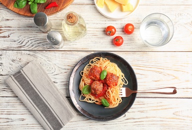 Photo of Delicious pasta with meatballs and tomato sauce on wooden background, flat lay