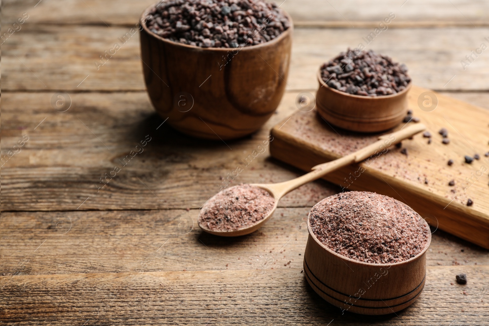 Photo of Natural black salt on wooden table. Space for text