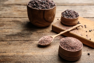 Photo of Natural black salt on wooden table. Space for text