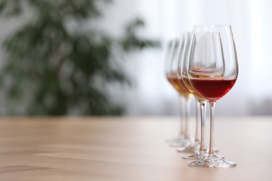 Photo of Different sorts of wine in glasses on wooden table indoors. Space for text