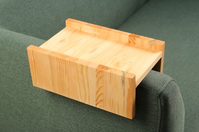 Photo of Wooden armrest table on sofa in room. Interior element