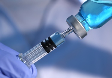 Photo of Woman filling syringe with vaccine from vial, closeup