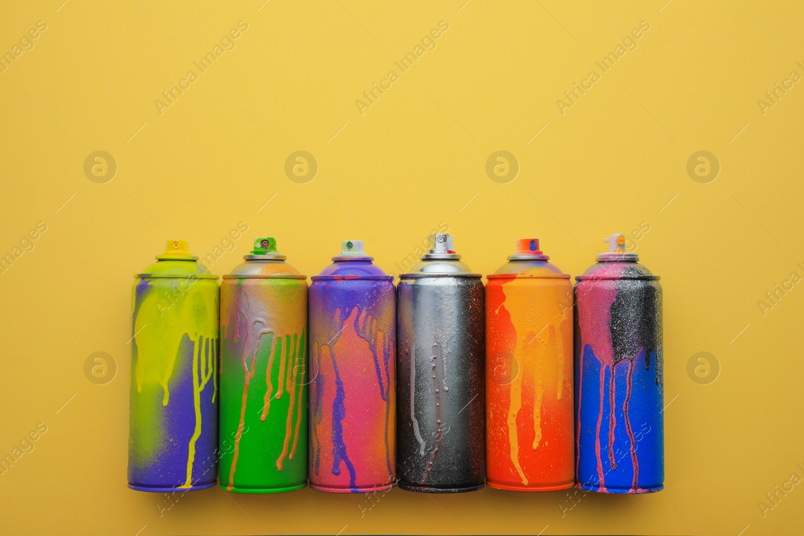Photo of Used cans of spray paints on beige background, flat lay with space for text. Graffiti supplies