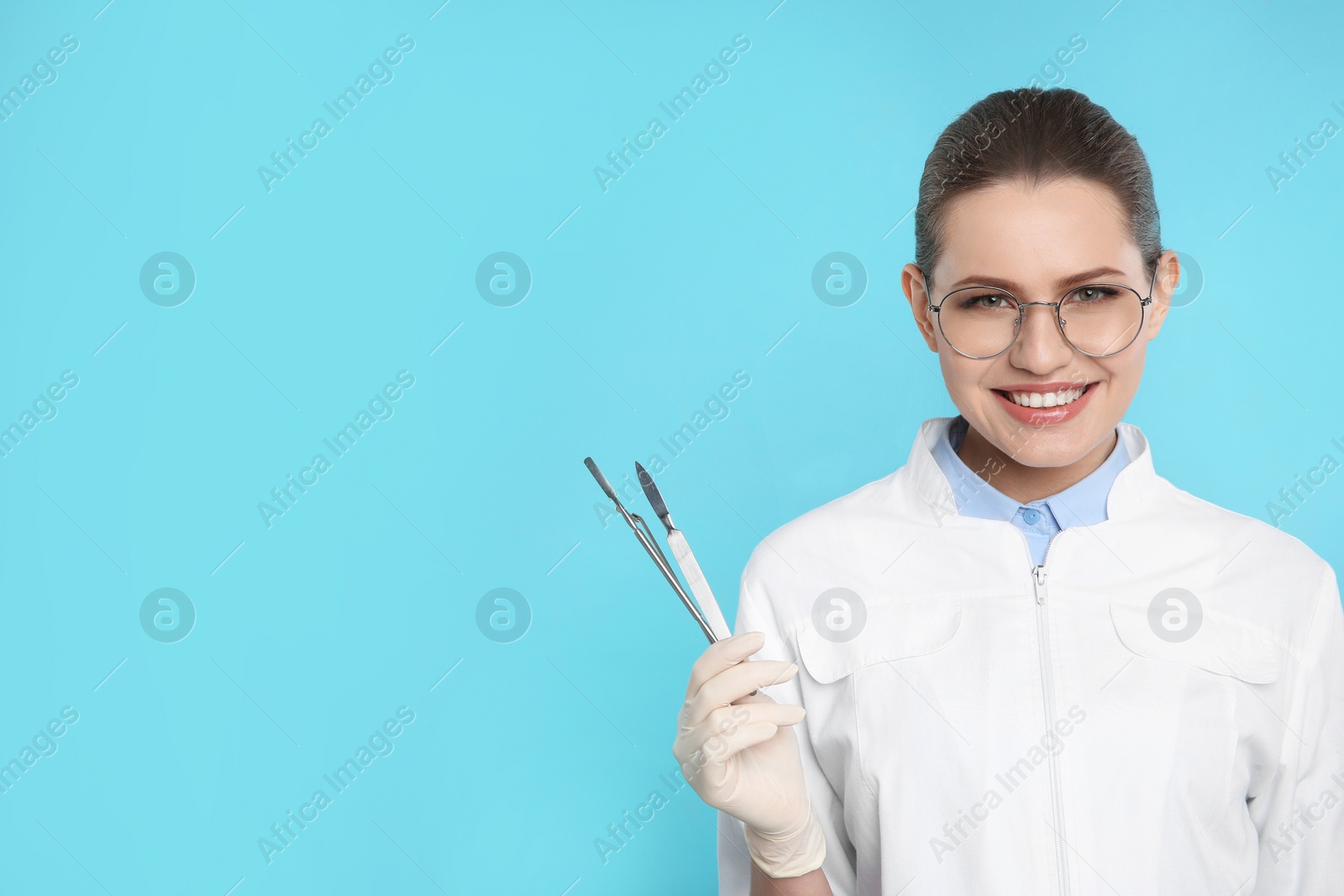 Photo of Female dentist holding professional tools on color background. Space for text