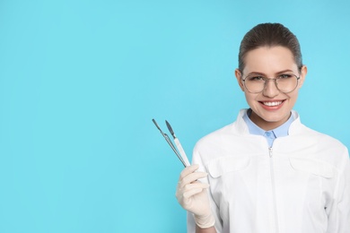Photo of Female dentist holding professional tools on color background. Space for text