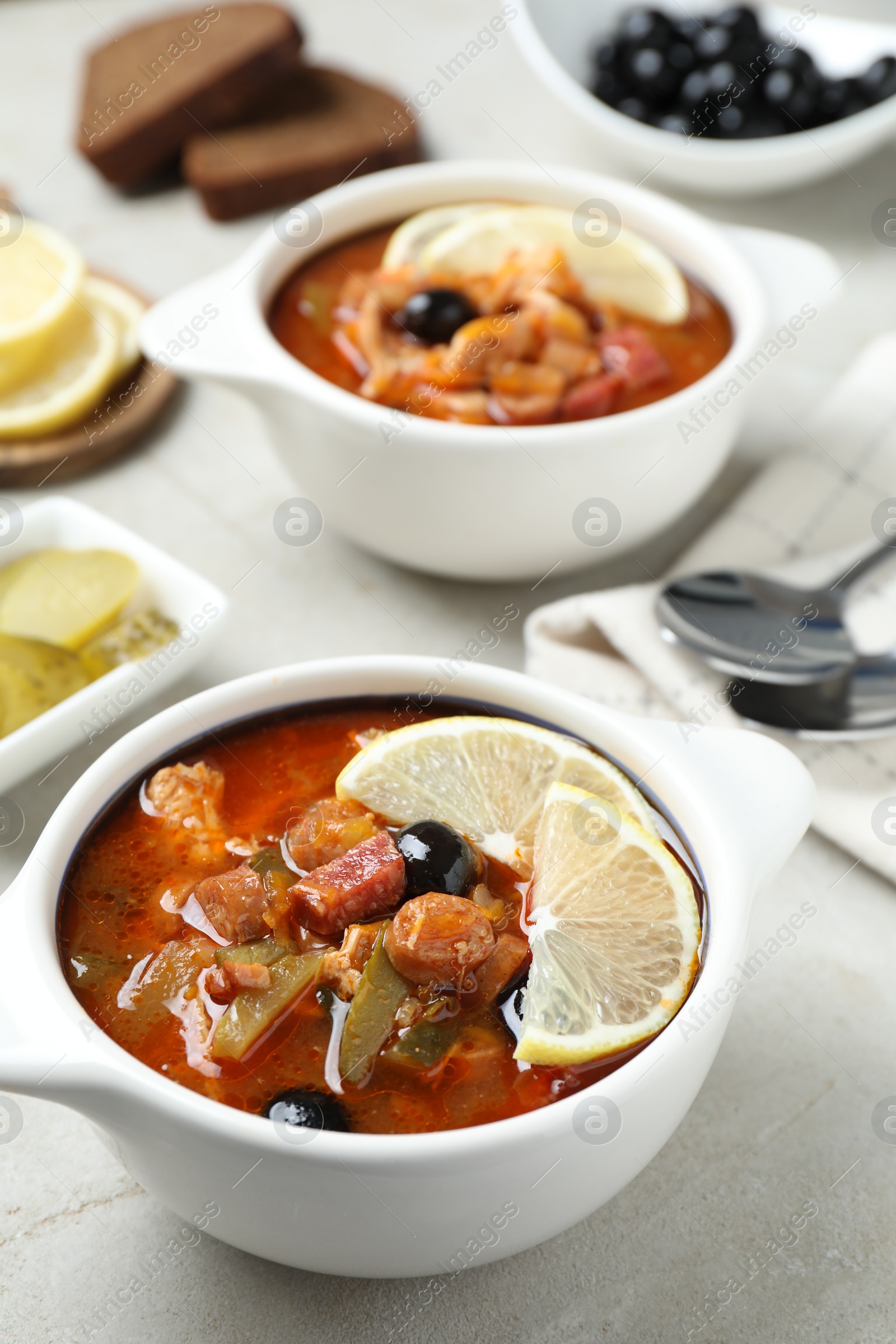 Photo of Meat solyanka soup with sausages, olives and vegetables on white table