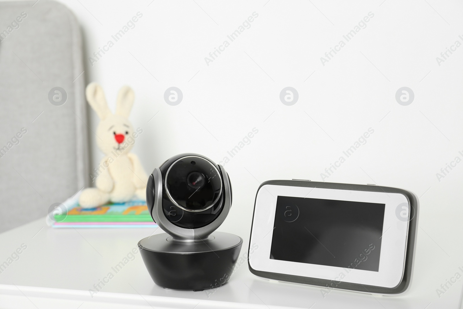 Photo of Baby monitor with camera on table against white wall. Video nanny