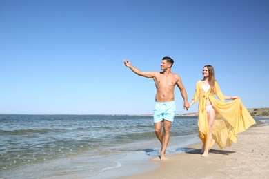 Photo of Woman in bikini and her boyfriend on beach, space for text. Happy couple