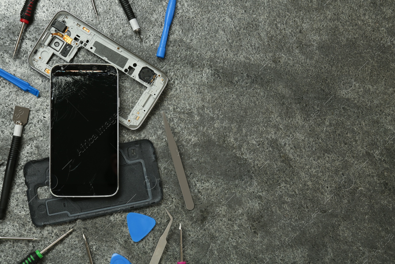 Photo of Parts of damaged smartphone and repair tool set on grey table, flat lay. Space for text