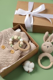 Photo of Different baby accessories, knitted clothes and cotton flower on green background