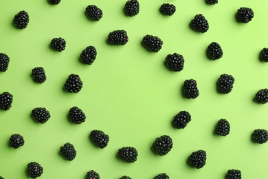 Frame made with fresh blackberries on green background, top view. Space for text