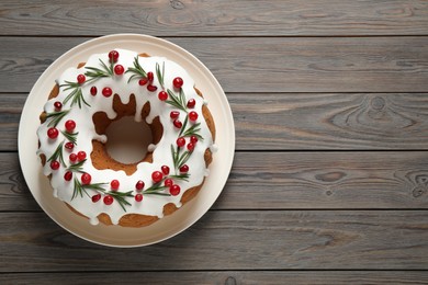 Photo of Traditional Christmas cake decorated with glaze, pomegranate seeds, cranberries and rosemary on wooden table, top view. Space for text