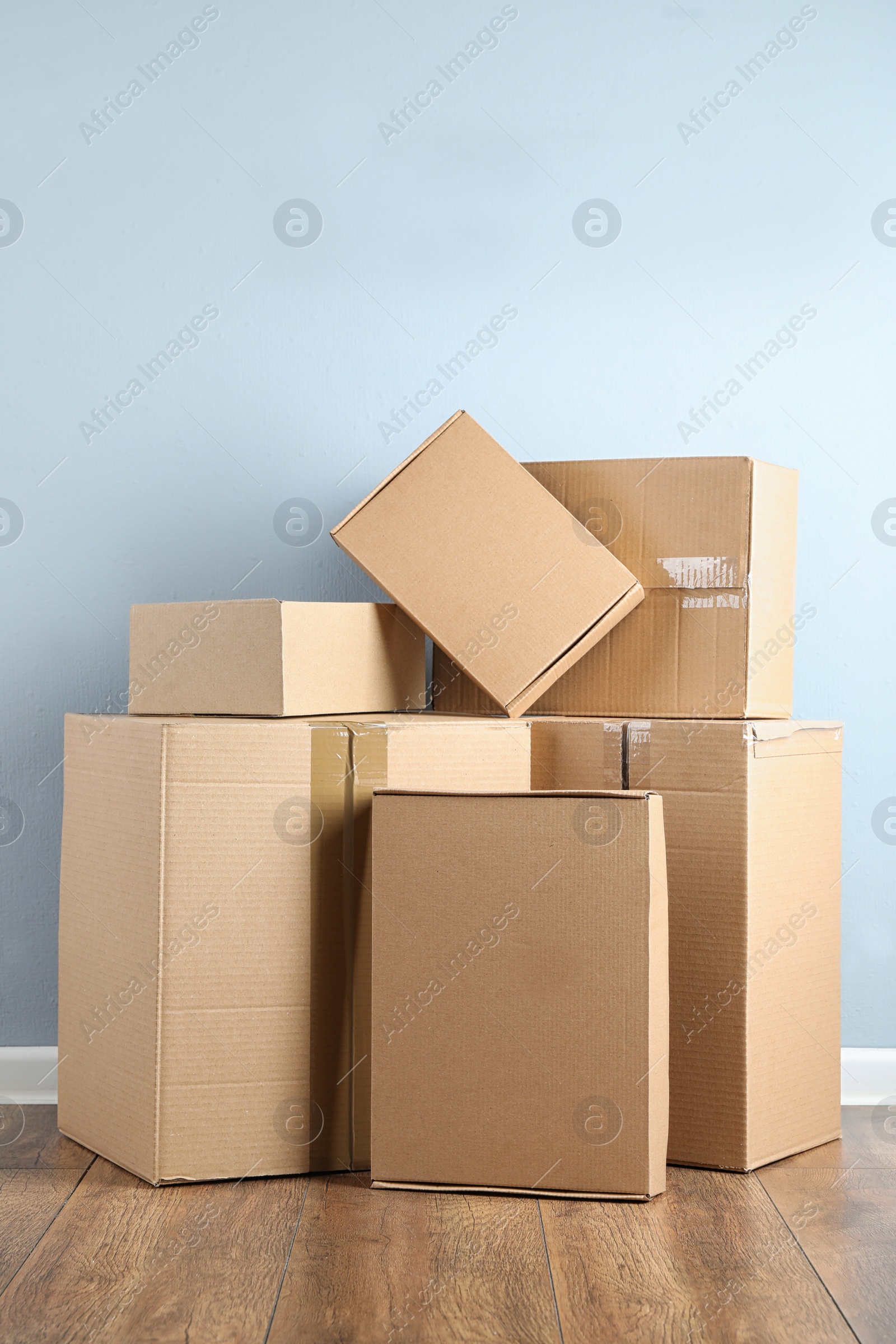 Photo of Pile of cardboard boxes near light blue wall indoors