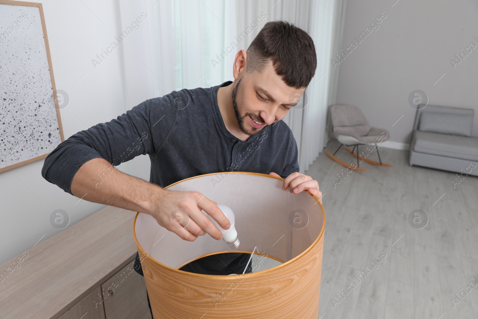 Photo of Man changing light bulb in lamp at home