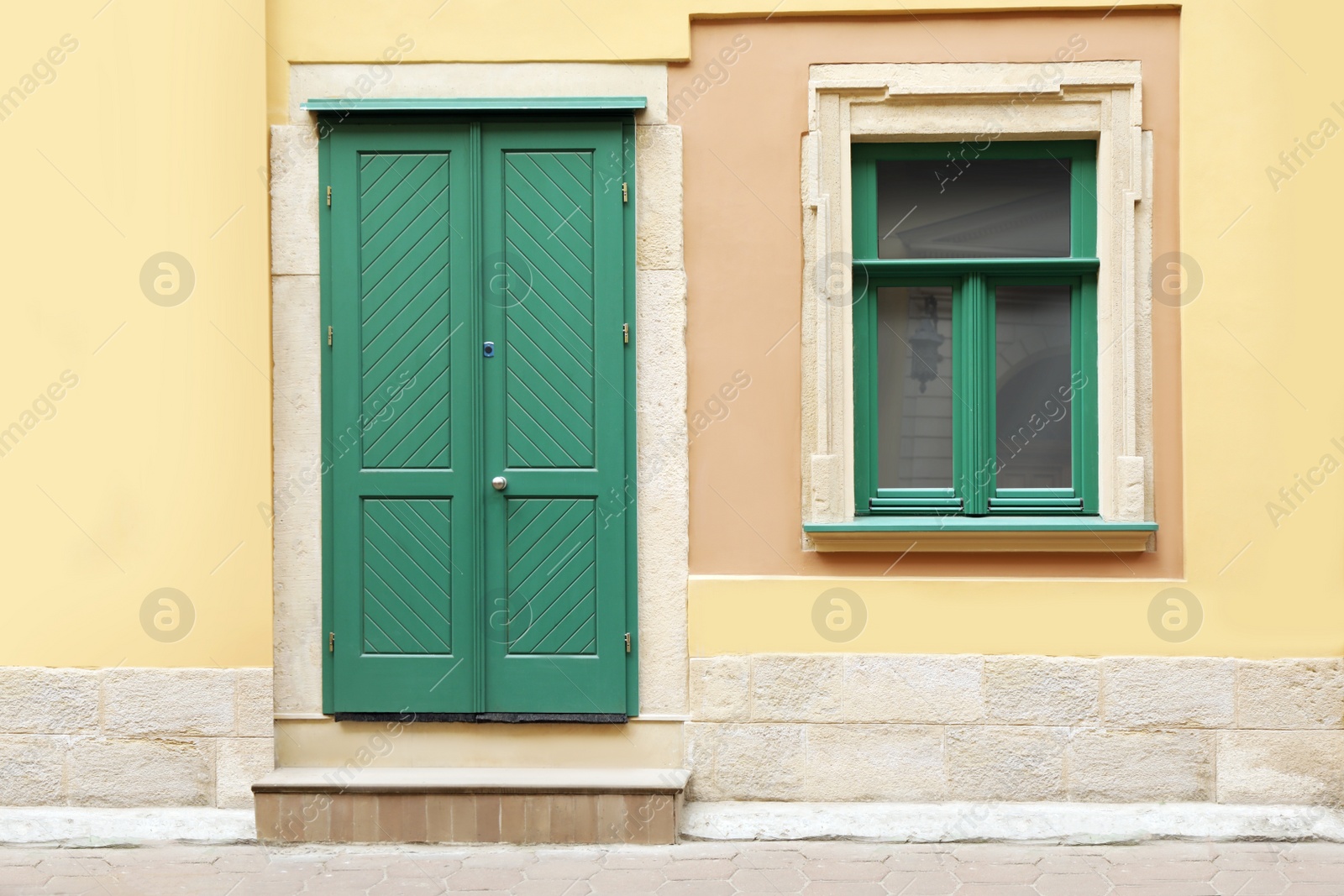 Photo of View of building with turquoise wooden door and window. Exterior design