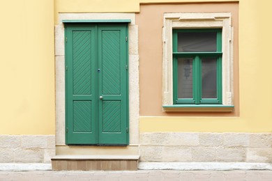 View of building with turquoise wooden door and window. Exterior design