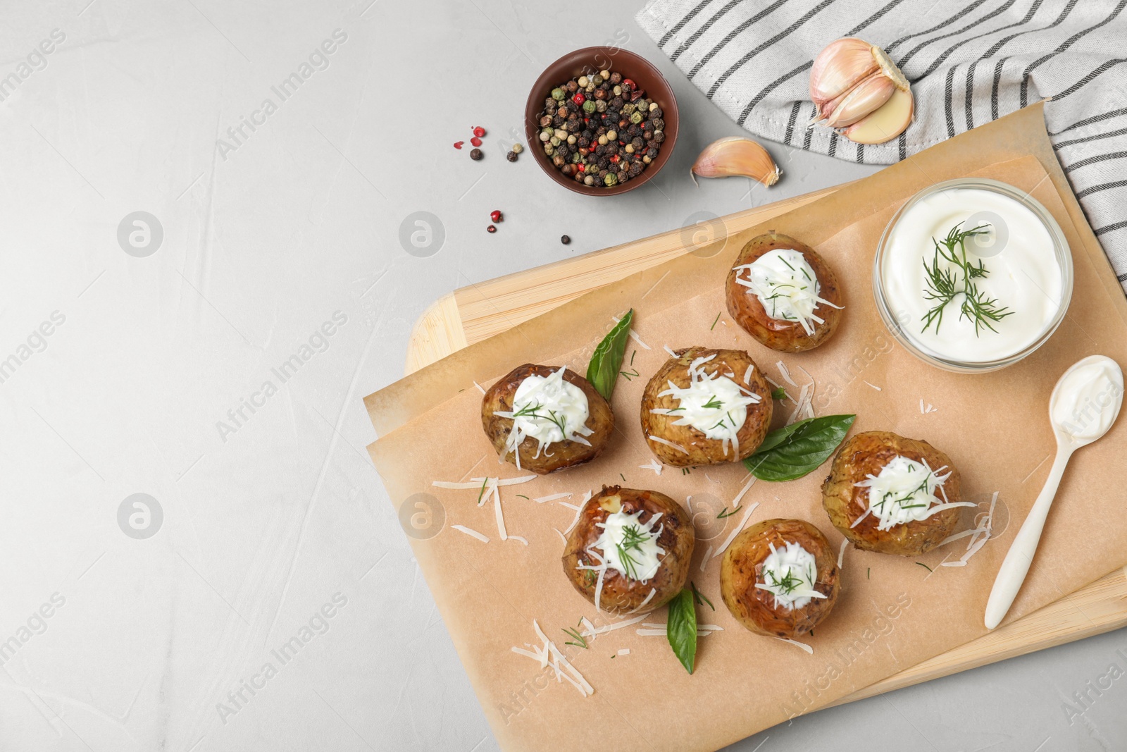 Photo of Delicious baked potato with sour cream served on light grey table, flat lay. Space for text