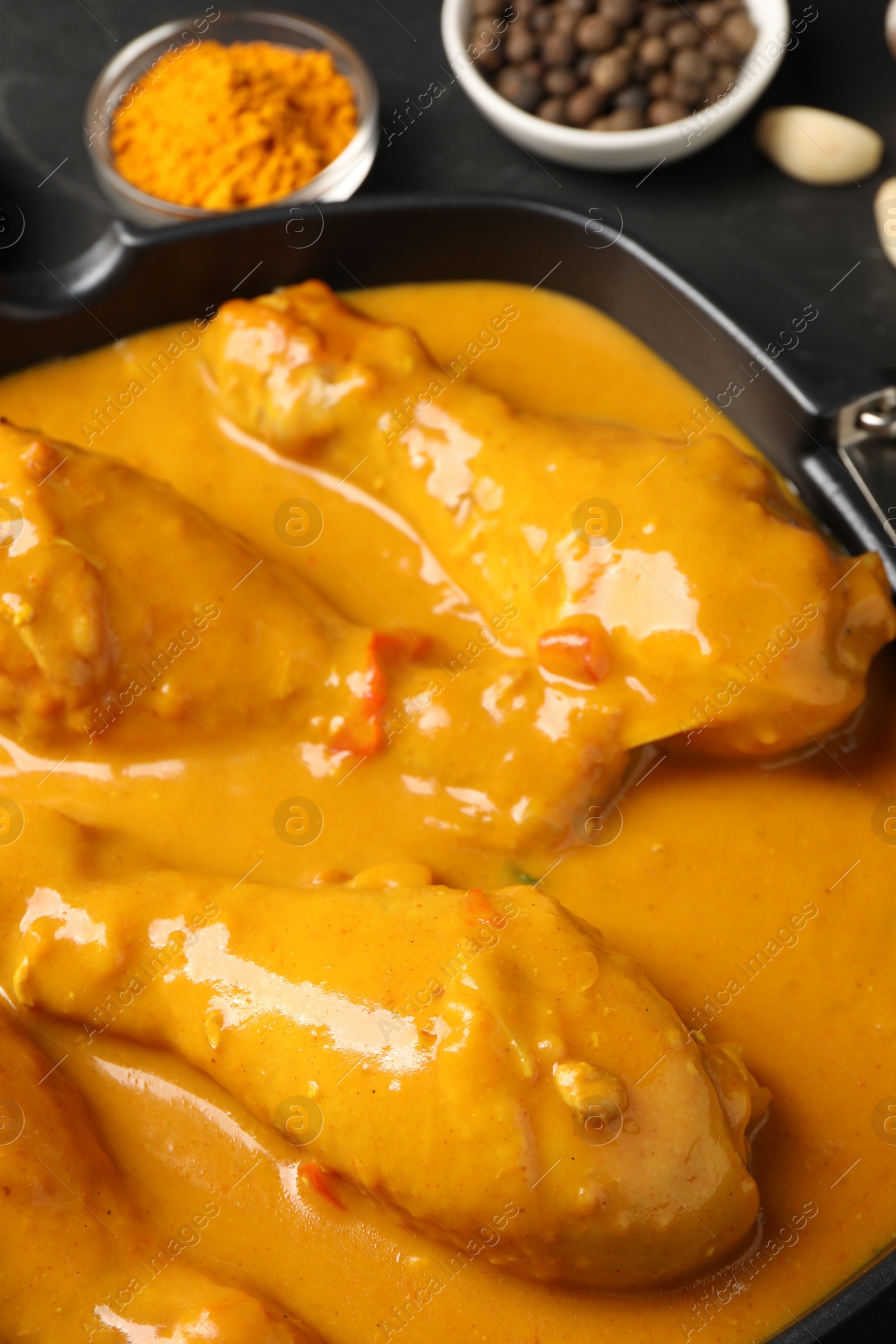 Photo of Tasty chicken curry and ingredients on black table