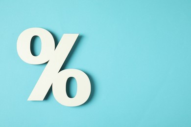 Photo of White percent sign on light blue background, top view. Space for text