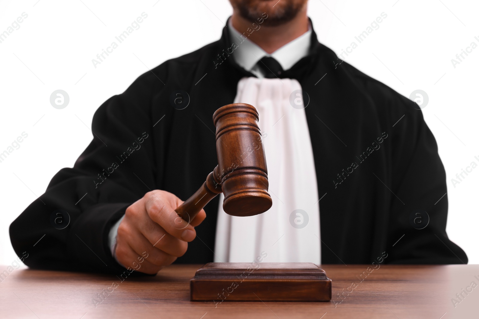 Photo of Judge with gavel at wooden table on white background, closeup