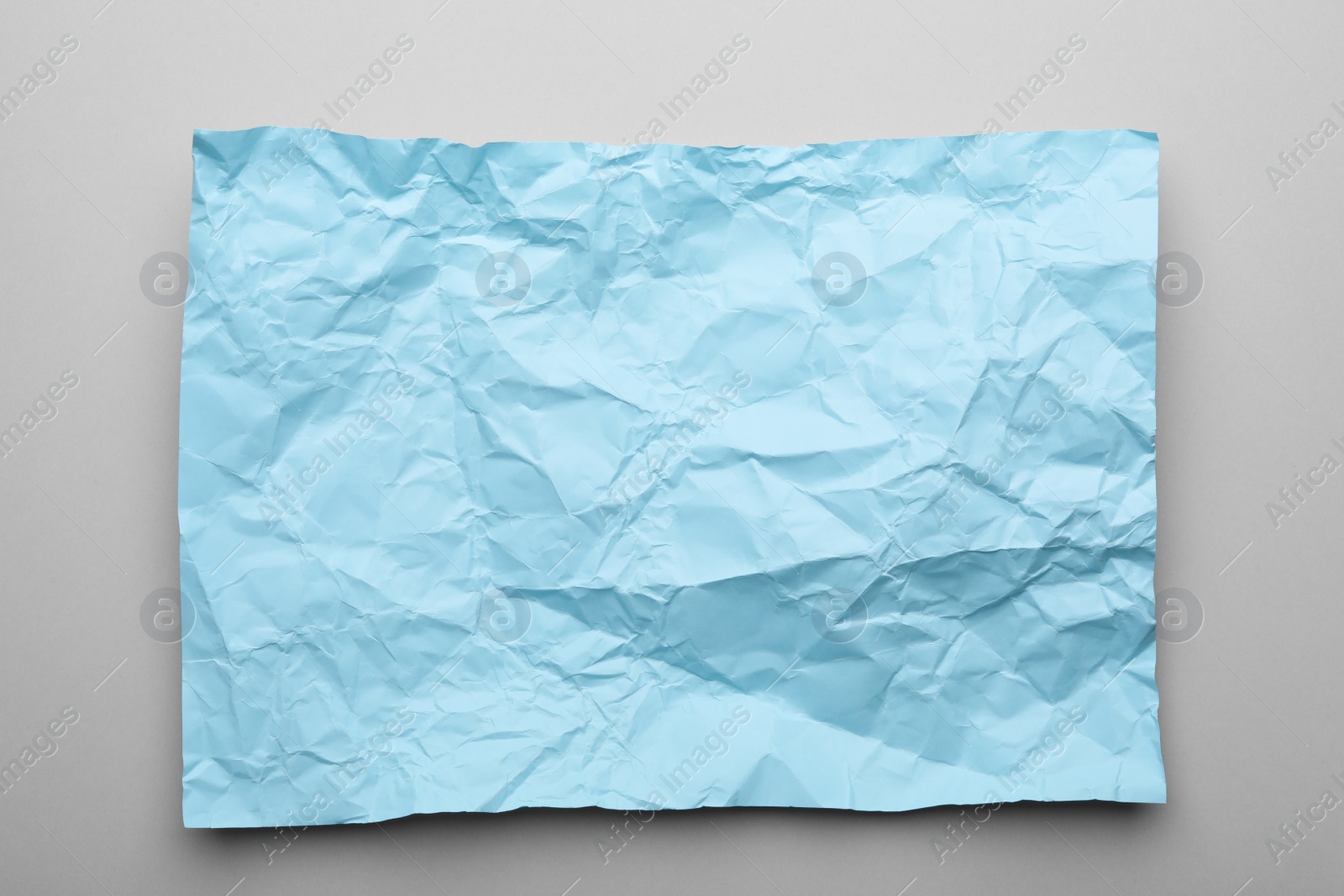 Photo of Color sheet of crumpled paper on grey background, top view
