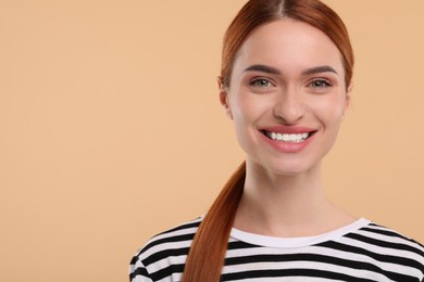 Beautiful woman with clean teeth smiling on beige background, space for text