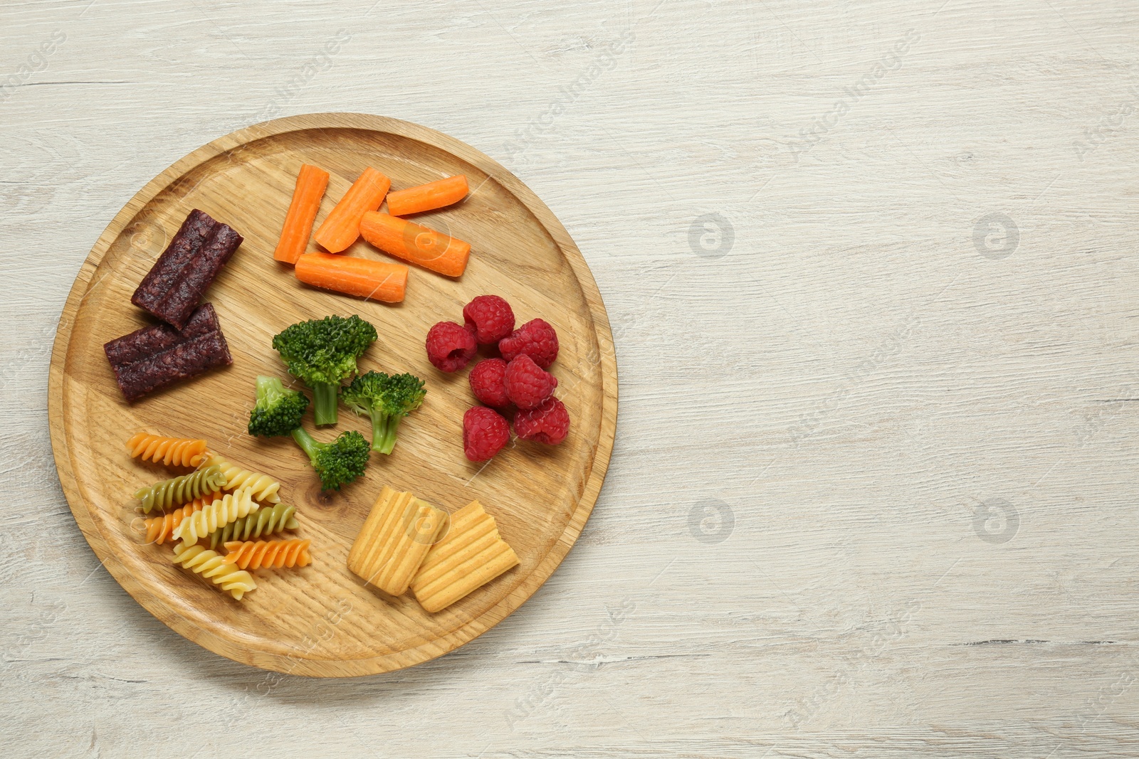 Photo of Board with different delicious baby finger foods on wooden table, top view. Space for text