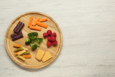 Photo of Board with different delicious baby finger foods on wooden table, top view. Space for text