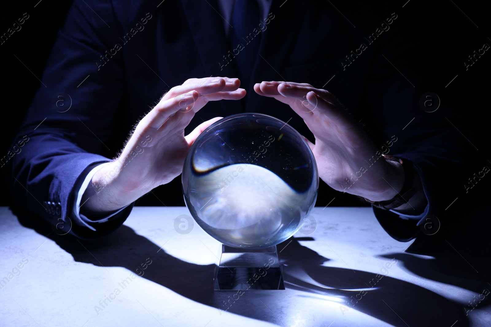 Photo of Businessman using crystal ball to predict future at table in darkness, closeup