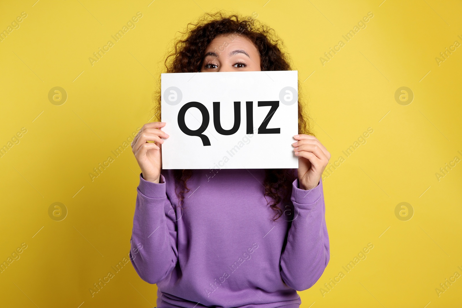Image of African American woman holding sign with word QUIZ on yellow background