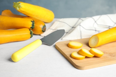 Photo of Fresh ripe yellow zucchinis on white wooden table against blue background