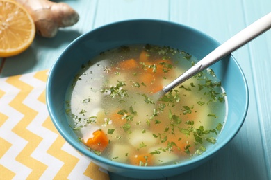 Photo of Bowl of fresh homemade soup to cure flu on wooden table