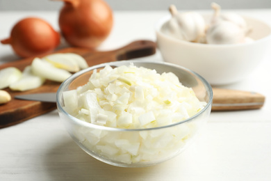 Photo of Chopped onion in bowl on white wooden table