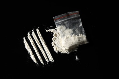 Photo of Drug addiction. Plastic bag with cocaine on black background, flat lay