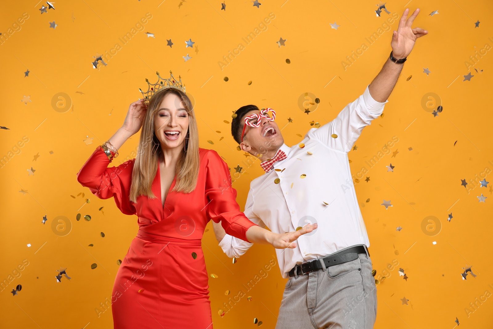 Photo of Happy couple and confetti on yellow background