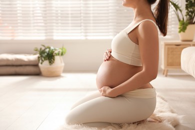 Photo of Young pregnant woman practicing yoga at home, closeup. Space for text